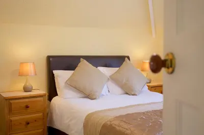 a bedroom with a bed with white pillows and two lamps at Little Coombe in St Ives