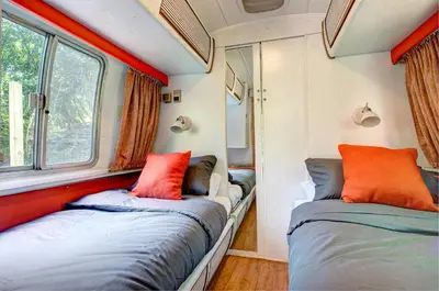 two beds in a small room with two windows at Glamping 1970 American Airstream motorhome in Ponsanooth