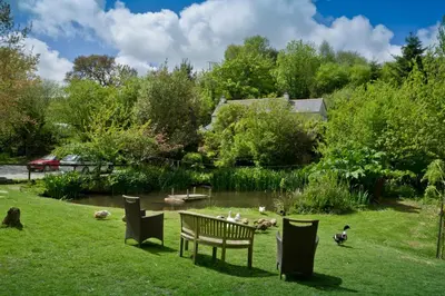 a park with a bench and a pond with ducks at Glamping 1970 American Airstream motorhome in Ponsanooth
