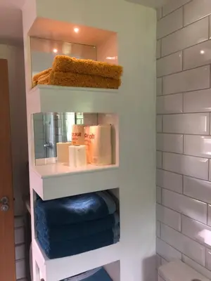 a bathroom with a shelf with towels and a mirror at Flat 7, Tremorvah Court in Falmouth