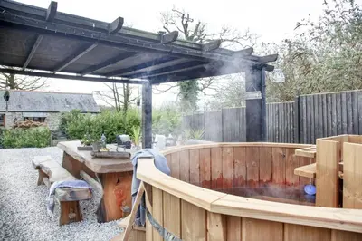 a wooden deck with a wooden table and aburningificialificialificialificialificialificial at The Barn in Lanhydrock, Bodmin in Bodmin