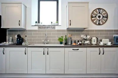 a kitchen with white cabinets and a clock on the wall at The Barn in Lanhydrock, Bodmin in Bodmin