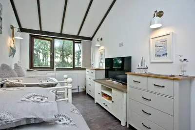 a bedroom with a bed and a desk and a tv at The Barn in Lanhydrock, Bodmin in Bodmin
