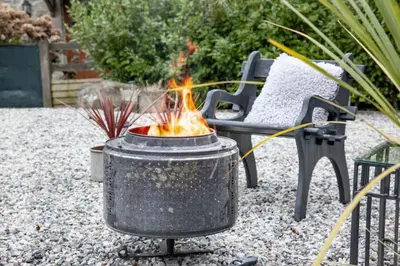 a grill with a fire in it in a yard at The Barn in Lanhydrock, Bodmin in Bodmin