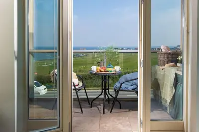 a sliding glass door with a view of a patio with a table at 5 The Vista, Newquay - Short Walk to Beach - Free Parking and Wi-Fi - Stunning Views in Newquay