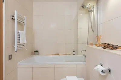 a white bathroom with a tub and a toilet at 5 The Vista, Newquay - Short Walk to Beach - Free Parking and Wi-Fi - Stunning Views in Newquay