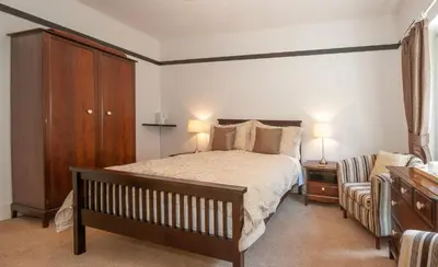 a bedroom with a bed and a cabinet and a chair at Natal House Bed & Breakfast in Polperro