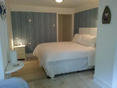 a bedroom with a white bed and a white table at Natal House Bed & Breakfast in Polperro