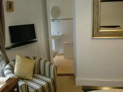 a living room with a chair and a television at Natal House Bed & Breakfast in Polperro