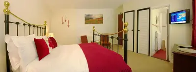 a bedroom with a bed with red and white pillows at Natal House Bed & Breakfast in Polperro