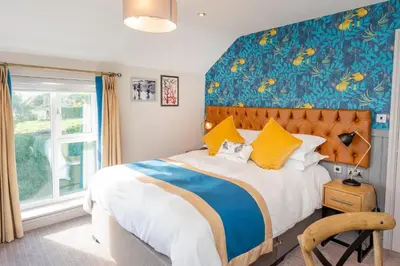 a bedroom with a large bed with a blue wall at The Inn on the Shore in Torpoint