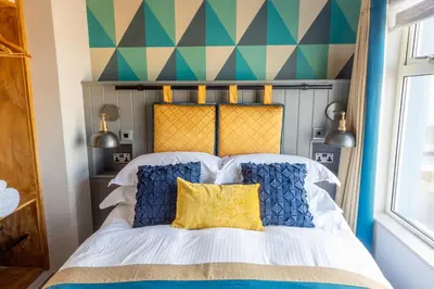 a bedroom with a bed with blue and yellow pillows at The Inn on the Shore in Torpoint