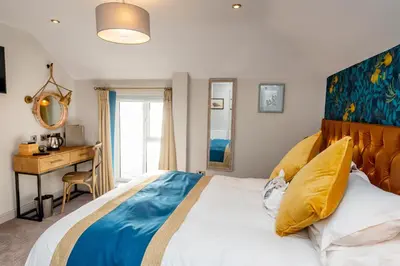 a bedroom with a large bed and a desk at The Inn on the Shore in Torpoint