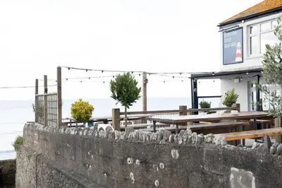 a restaurant with a stone wall and tables and the ocean at The Inn on the Shore in Torpoint