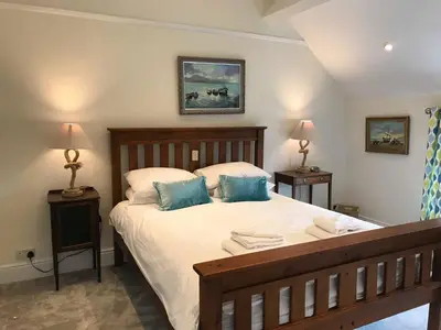 a bedroom with a large bed with blue pillows at Buller Cottage in Cornwall in Newquay