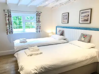 two twin beds in a room with a window at Buller Cottage in Cornwall in Newquay