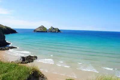 a beach with some rocks in the ocean at Buller Cottage in Cornwall in Newquay