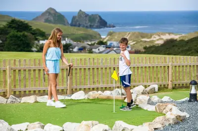 a woman and a boy standing on a golf course at Buller Cottage in Cornwall in Newquay