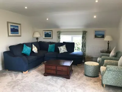 a living room with a blue couch and two chairs at Buller Cottage in Cornwall in Newquay