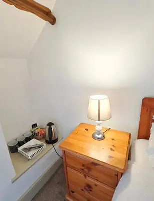 a bedroom with a table with a lamp on a dresser at The Darlington Hotel in Camelford