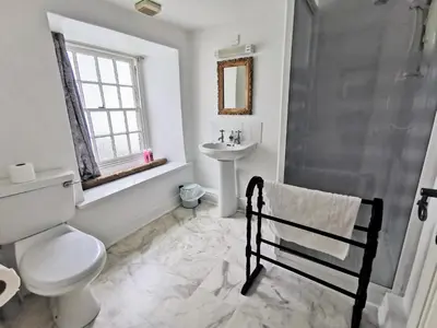 a white bathroom with a toilet and a sink at The Darlington Hotel in Camelford