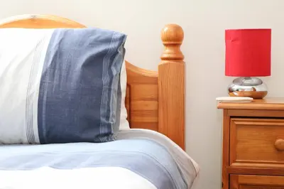 a bed with a blue pillow and a red lamp at TOWN CENTRE apartment dogs welcome in Padstow