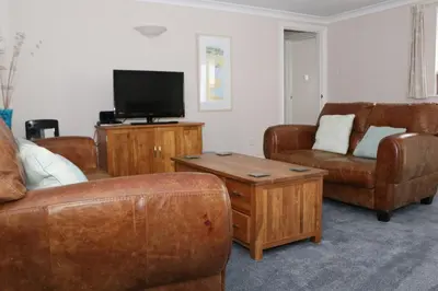 a living room with leather furniture and a flat screen tv at TOWN CENTRE apartment with parking in Padstow
