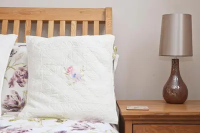 a bed with a pillow and a lamp on a night stand at TOWN CENTRE apartment with parking in Padstow