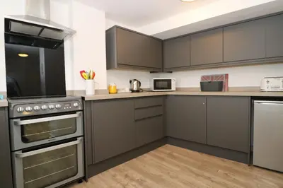 a kitchen with gray cabinets and stainless steel appliances at TOWN CENTRE apartment with parking in Padstow