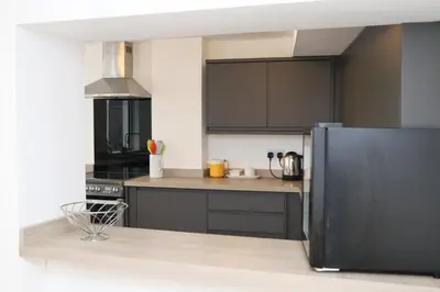 a kitchen with black cabinets and a stainless steel refrigerator at TOWN CENTRE apartment with parking in Padstow