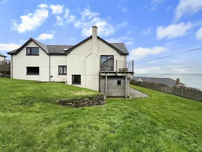 a large white house on a grassy field at Porthleven Coastal Retreat with 5 Bedrooms in Porthleven