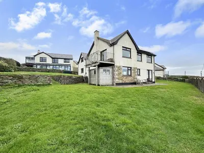 a large house on top of a grass field at Porthleven Coastal Retreat with 5 Bedrooms in Porthleven