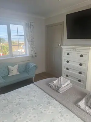 a bedroom with a bed and a dresser with a television at Downsfield Bed and Breakfast in St Ives