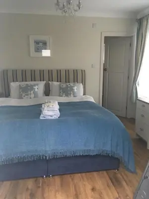 a bedroom with a bed with a blue blanket at Downsfield Bed and Breakfast in St Ives
