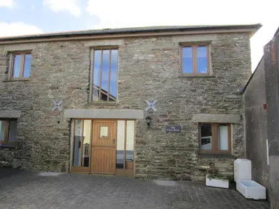 an old stone house with wooden doors and windows at The Corn Store in Porthtowan