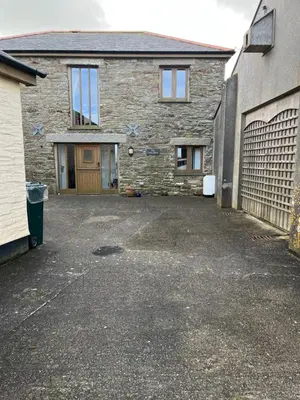 a stone house with a parking lot in front of it at The Corn Store in Porthtowan
