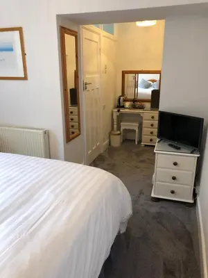 a bedroom with a bed and a tv and a mirror at Beacon Country House B & B & Luxury Shepherd Huts in St. Agnes