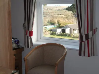 a chair sitting in a room with a window at Beacon Country House B & B & Luxury Shepherd Huts in St. Agnes