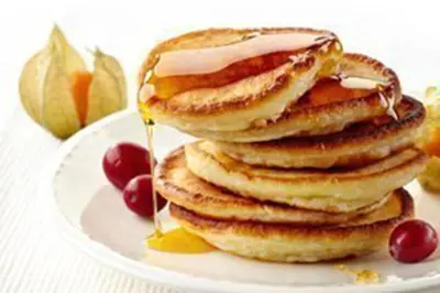 a stack of pancakes with syrup and cherries on a plate at Beacon Country House B & B & Luxury Shepherd Huts in St. Agnes