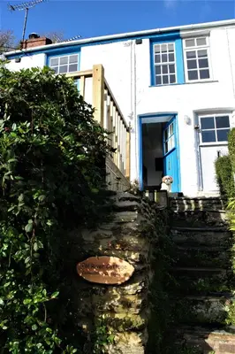 a stone staircase leading to a white house with a blue door at Fal River Cottage in Truro