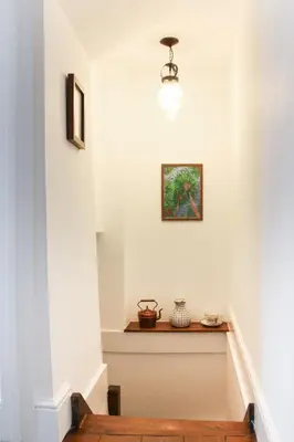 a staircase in a house with a picture on the wall at Fal River Cottage in Truro