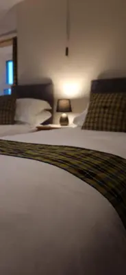 a bedroom with two beds and a table with a lamp at Sycamore Farm in Launceston