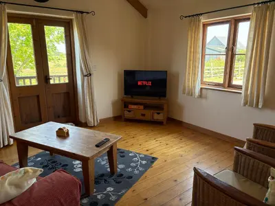 a living room with a table and a tv at The Byre in Porthtowan