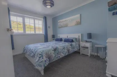a blue bedroom with a bed and a window at Inner Harbour Cottage in Portreath