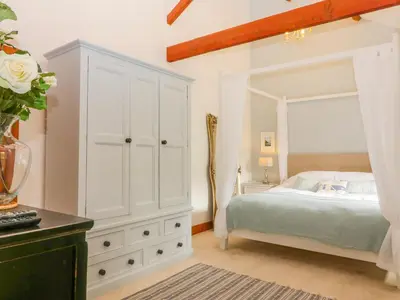 a white bedroom with a bed and a dresser at The Wagon House in Launceston