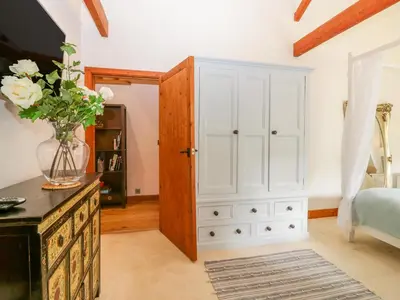 a bedroom with a white cabinet and a vase of flowers at The Wagon House in Launceston