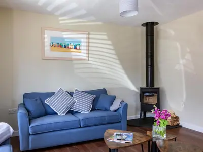 a living room with a blue couch and a wood stove at Rocky Close in St Ives
