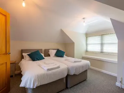 a bedroom with a bed with white sheets and blue pillows at Rocky Close in St Ives