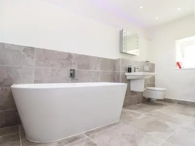 a bathroom with a large white tub and a toilet at Sunbury Barn in St. Agnes