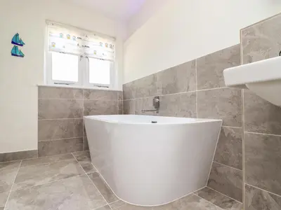 a white bath tub in a bathroom with a window at Sunbury Barn in St. Agnes